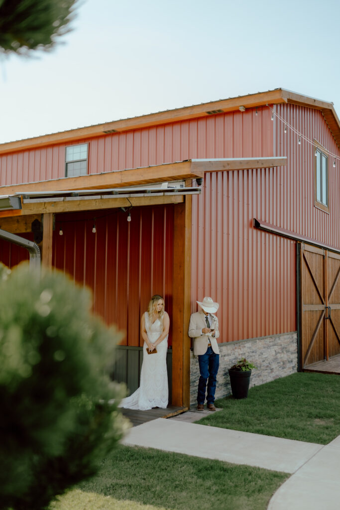 bride and groom share vows in front of red barn wedding venue