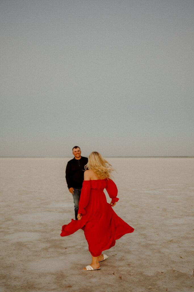 Engaged couple dancing on the wide-open salt flats of Oklahoma at sunset