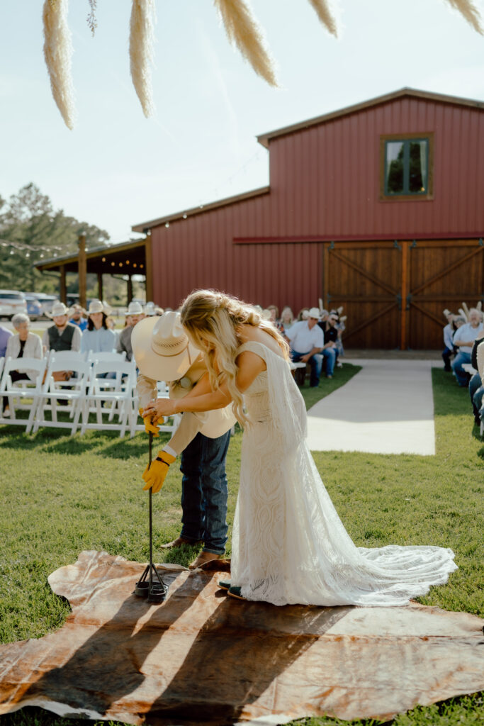 bride and groom branding cowhide at rustic oklahoma wedding venue