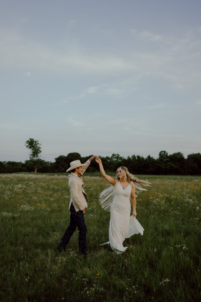 bride and groom dancing in field of wildflowers at rustic oklahoma wedding venue