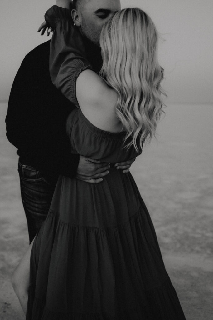 Engaged couple hugging on the wide-open salt flats of Oklahoma at sunset