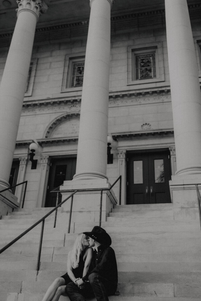 couple sitting on the steps kissing for a documentary style engagement photo