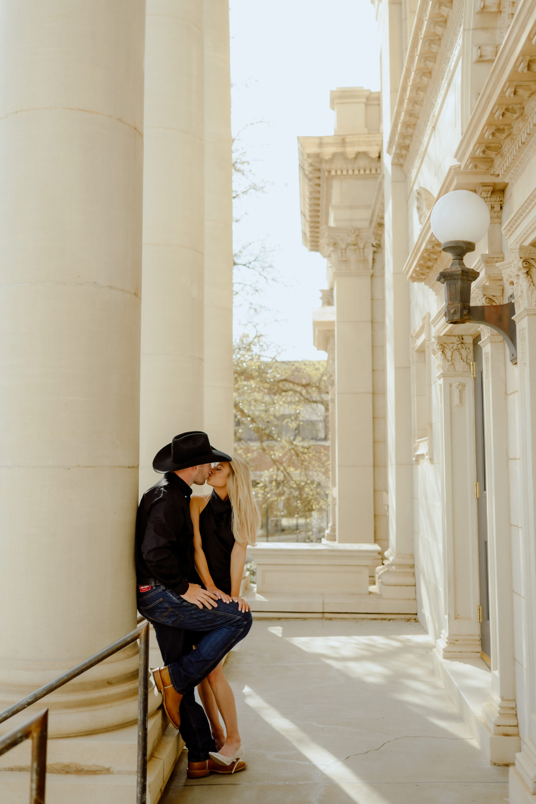 couple kissing at the top of the steps at their downtown engagement session documented by oklahoma city photographer