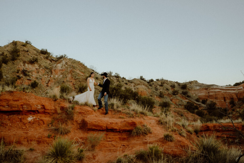 groom leads bride down the red bluffs at their texas elopement