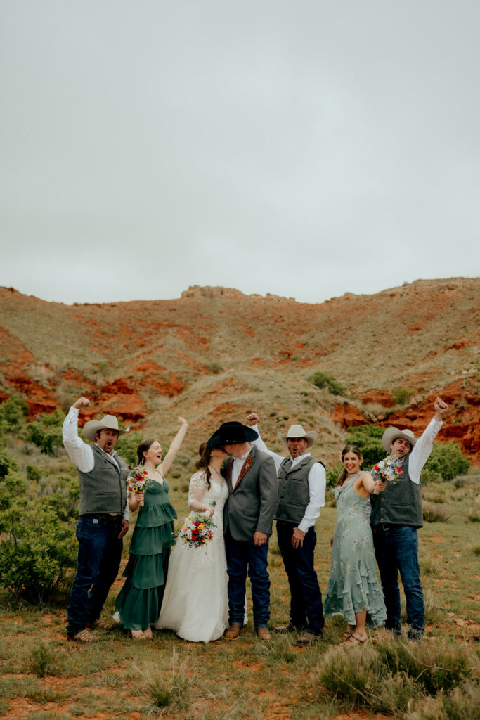 cowboy wedding party celebrates bride and groom kissing