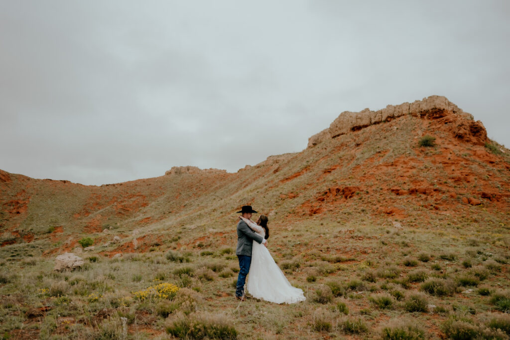 cowboy wedding bride and groom portrait against the red dirt bluffs
