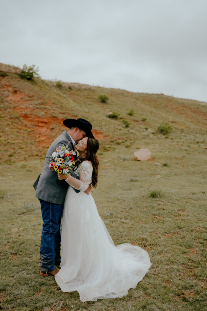groom kisses bride on the cheek at cowboy wedding