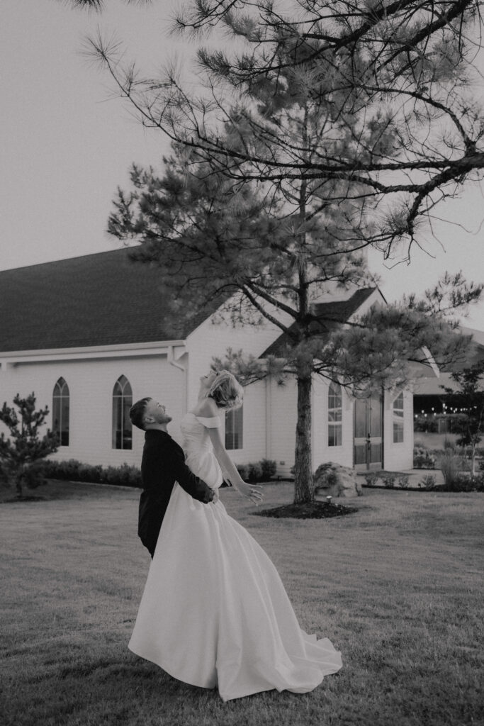 groom twirls bride around in front of the chapel at the springs wedding venue