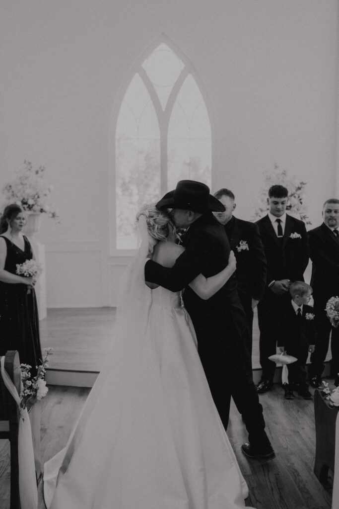 dad kisses daughters cheek at chapel wedding ceremony