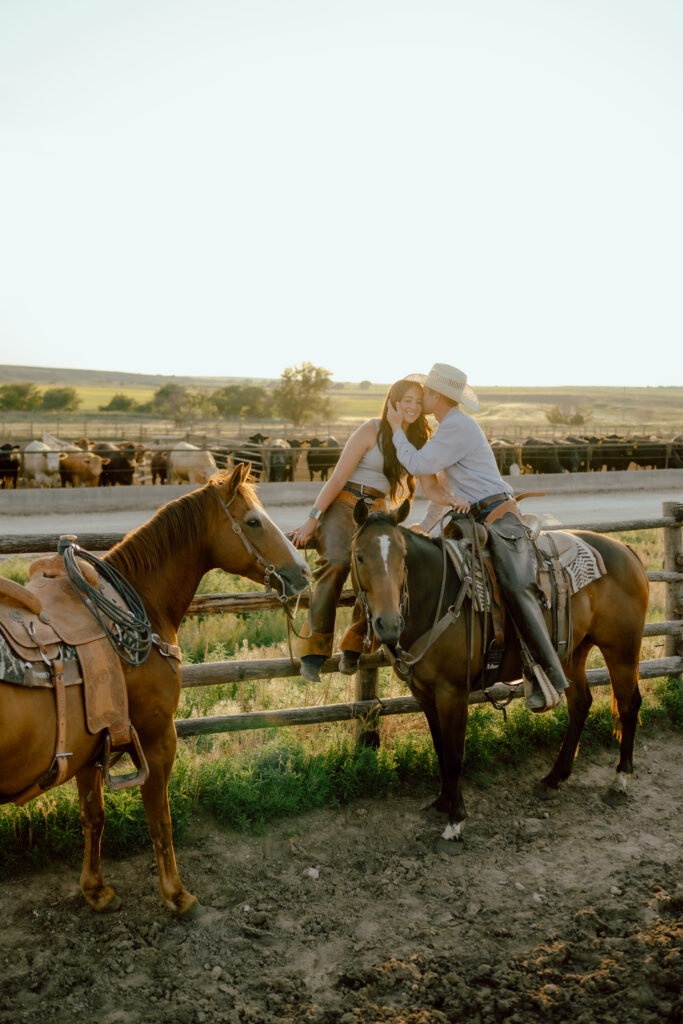 cowgirl sitting on wood fence while cowboy is horseback