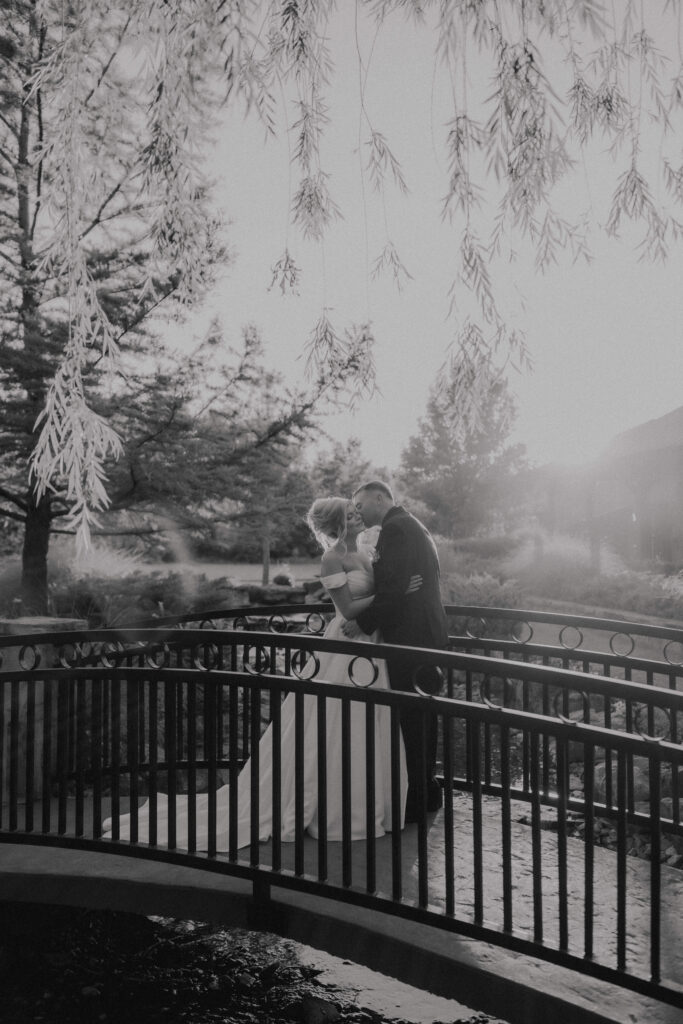 groom kisses brides cheek on the bridge at the springs venue