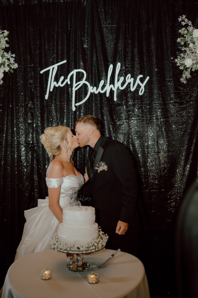 bride and groom kiss after cutting cake at the springs venue