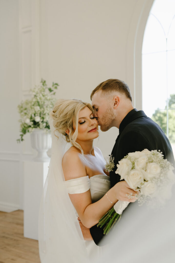bride and groom portrait inside white chapel wedding venue