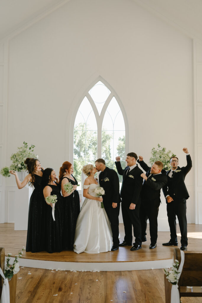 wedding party cheers as bride and groom kiss inside chapel at the springs